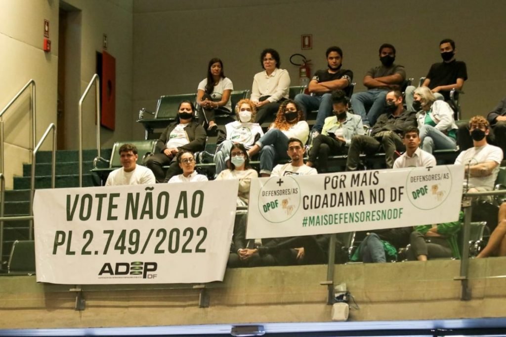pessoas sentadas com faixa à frente