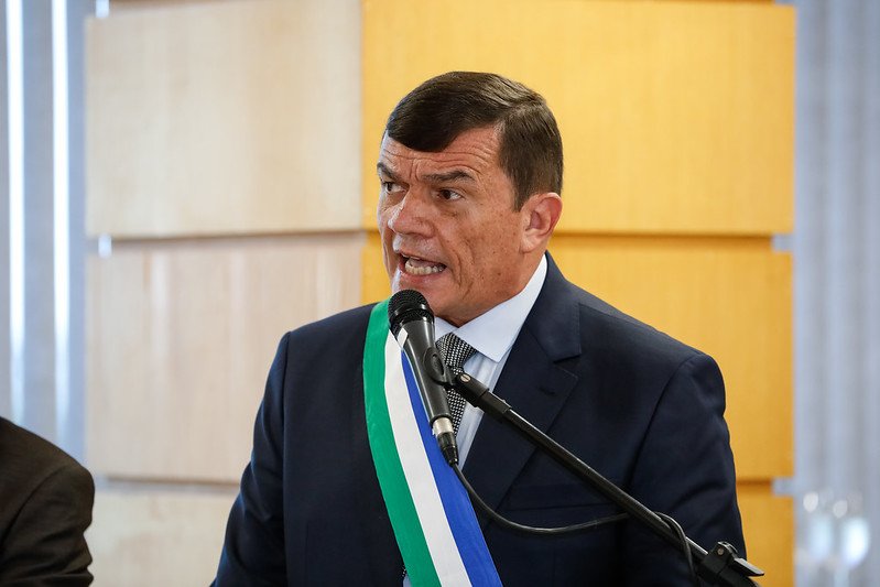 Paulo Sérgio Nogueira, ministro da Defesa, discursa em evento frente ao microfone. Ele usa faixa de cores verde, azul e branco - Metrópoles