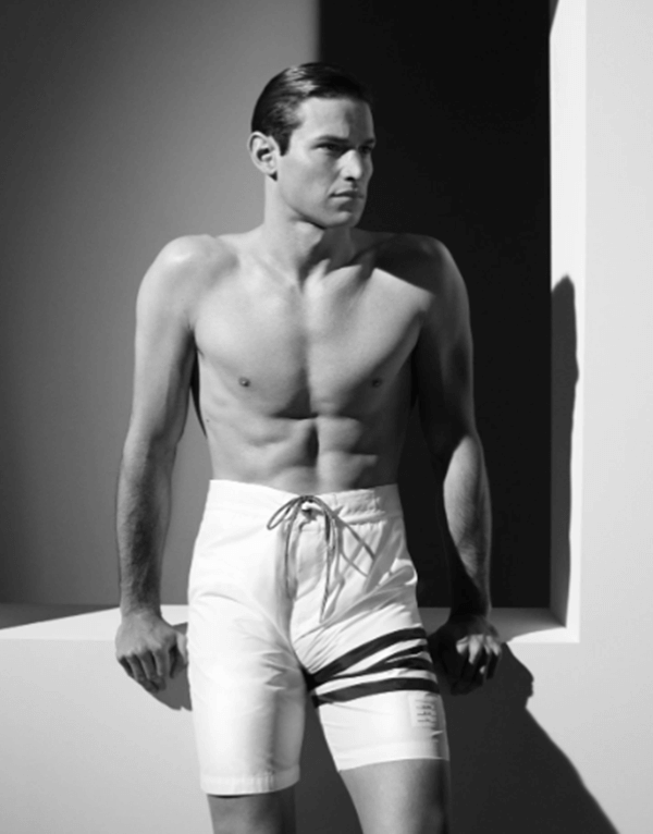 Na imagem em preto e branco, modelo sem camisa usa short da Thom Browne