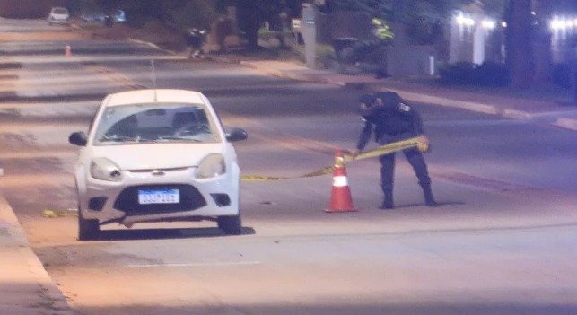 Carro branco parado em frente a uma faixa da policia- Metrópoles