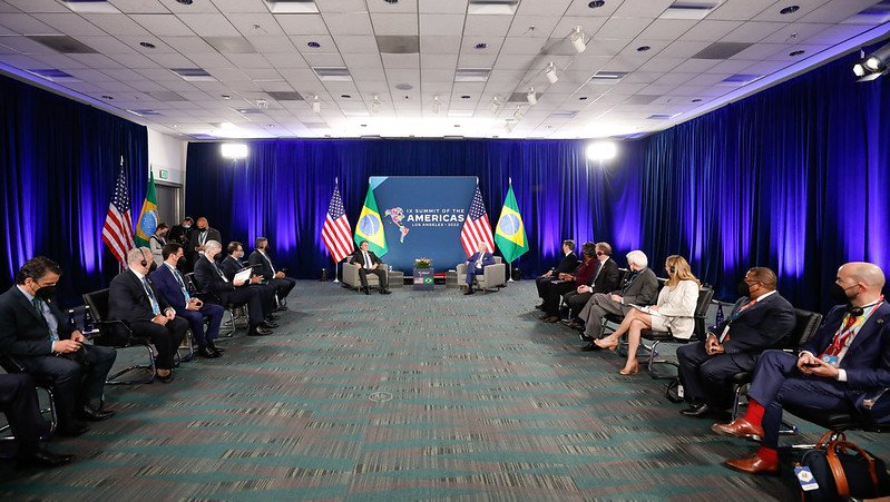 Uma série de pessoas assistem a uma reunião bilateral do presidente americano Joe Biden com Bolsonaro na Cúpula das Américas Ao fundo, as bandeiras dos Estados Unidos e Brasil - Metrópoles