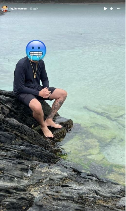 Jovem sentado em pedra na beira do mar