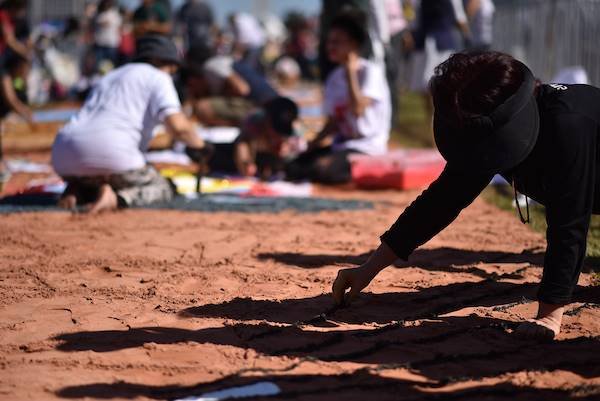 Pessoas reunidas na Esplanada em comemoração ao Corpus Christi próxima a tendas participam de confecção de tapete para a celebração - Metrópoles