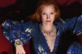 A atriz Jessica Chastain, uma mulher branca com cabelosos ruivos lisos e longos, posando para campanha publicitária de joias da marca Gucci. Na foto, ela usa um vestido azul com mangas bufantes, e detalhes brilhosos, e um colar e um brinco de diamantes com outras pedras preciosas.