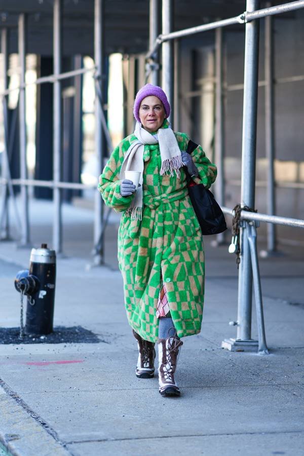 Mulher usa casaco com estampa verde, cachecol bege e touca lilás