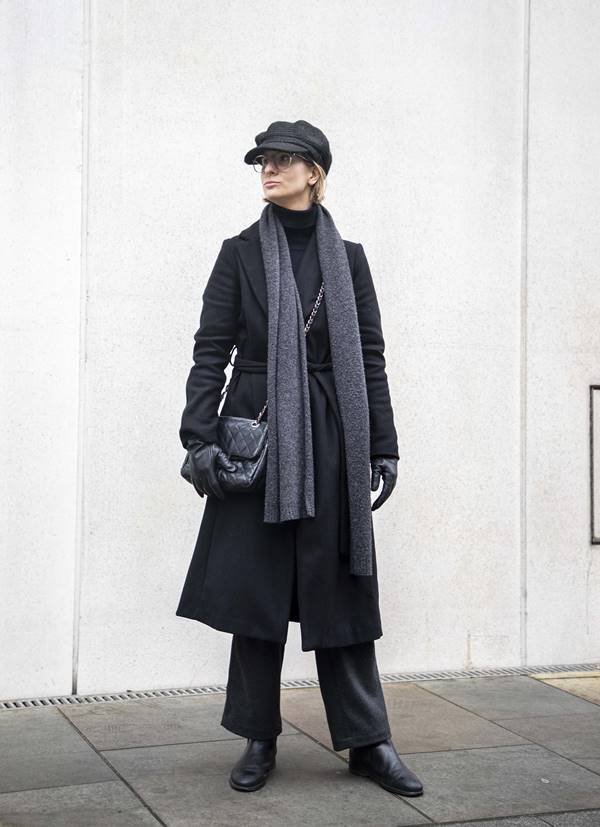 Em look preto e cinza, mulher usa boina, cachecol e luvas