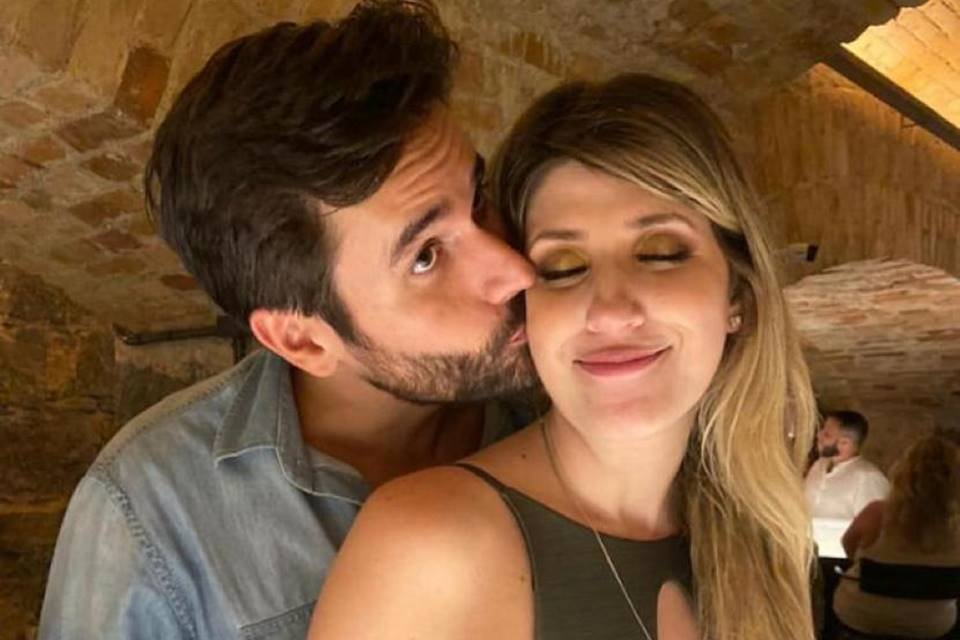 foto colorida de um homem abraçando uma mulher e beijando seu rosto