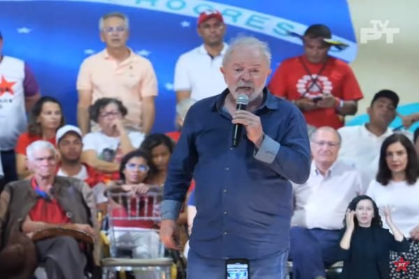Lula veste camisa social azul, segura um microfone e discursa em ato do Partido dos Trabalhadores