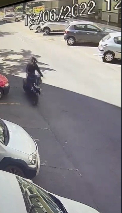 homem de capacete amarelo pilota moto entre carros estacionados