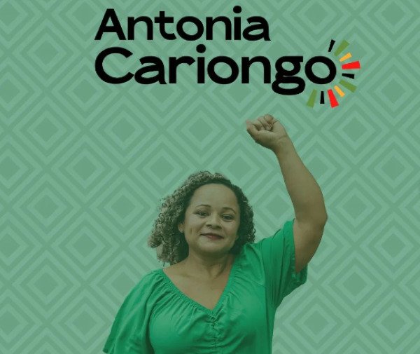 foto colorida de mulher com punho levantado e camisa verde