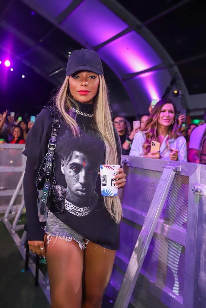 Na foto, mulher de boné e blusa de manga comprida pretas com um short jeans posa para a foto