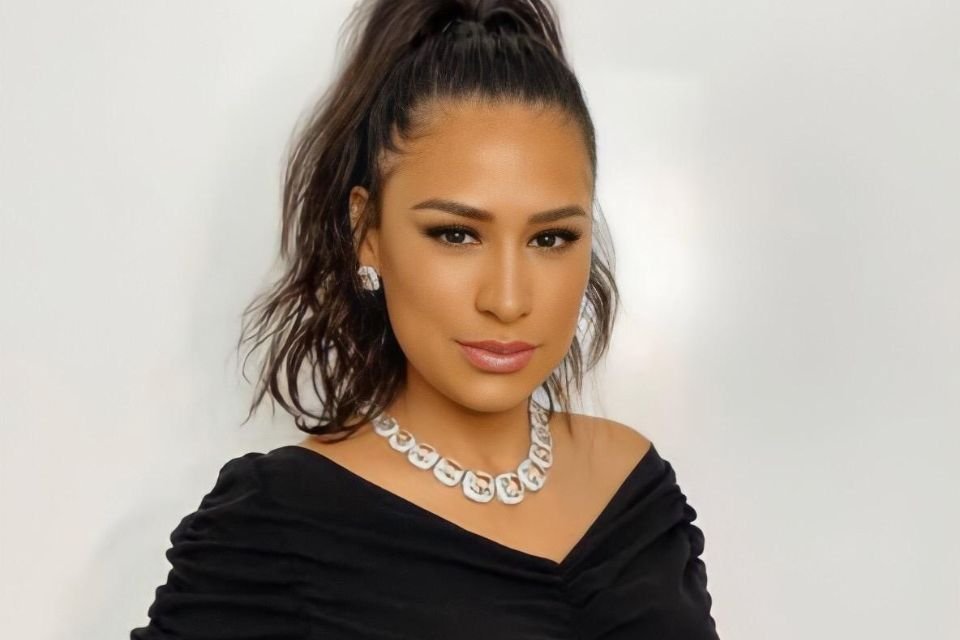 Mulher de rabo de cavalo usa vestido preto com decote em v e colar