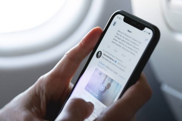 Pessoa mexendo no app Twitter no celular em avião - Metrópoles