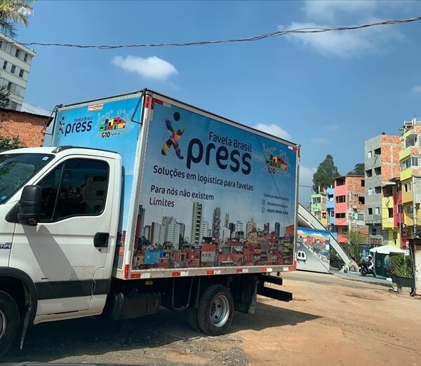 Na imagem com cor, caminhão de entregas com a logo da Favela Brasil Xpress