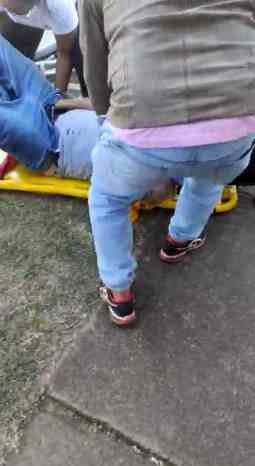 foto colorida de homem branco em cima de maca amarela com a mão na virilha