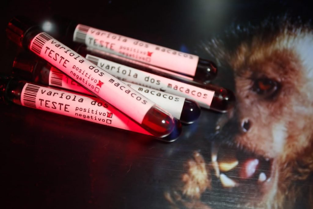 Dupla exposição de imagem de macaco prego e tubos de ensaio sinalizando resultado positivo para varíola dos macacos