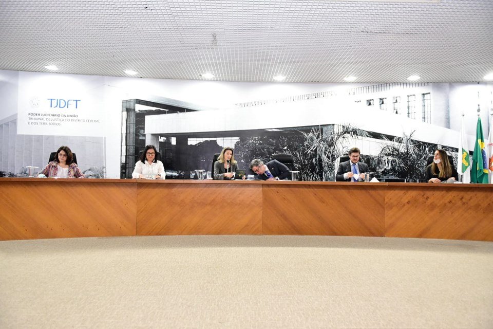 Pessoas sentadas atrás de mesa de madeira grande