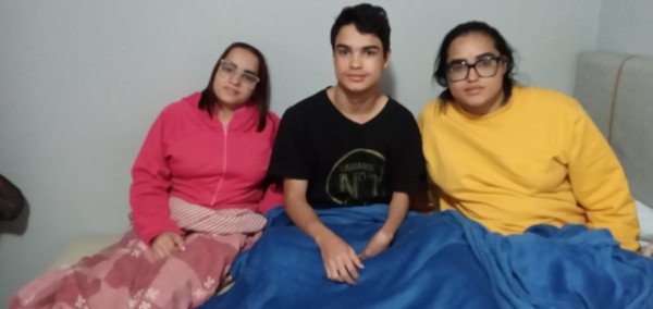 três pessoas olham para câmera