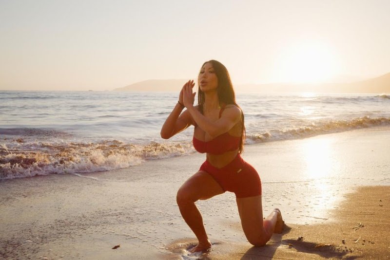 Mulher na praia agachada em um joelho