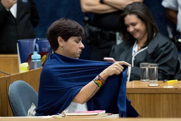Fotografia colorida de mulher ajustando lenço azul em volta dos ombros