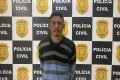 homem pardo com casaco listrado em frente ao painel da PCDF