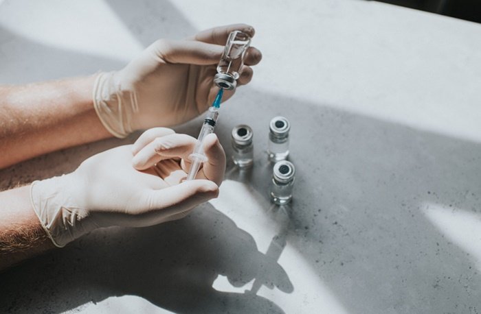 Syringe and gloved container with clear liquid - Metropolis