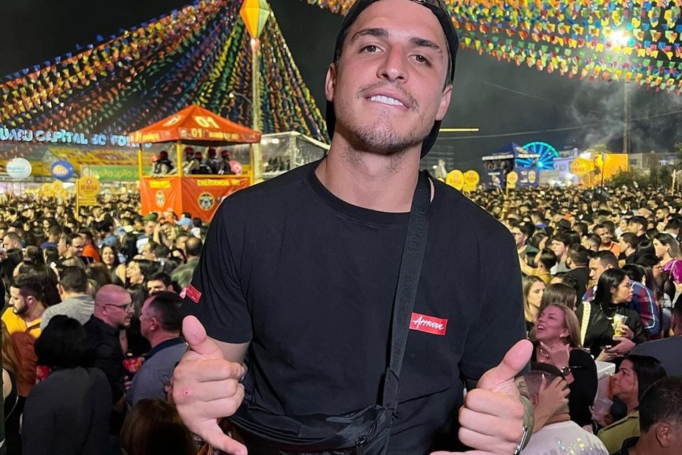 Felipe Prior, em foto para o Instagram. Ele veste um boné preto, camisa preta, uma bolsa no ombro e acena para a câmera - Metrópoles