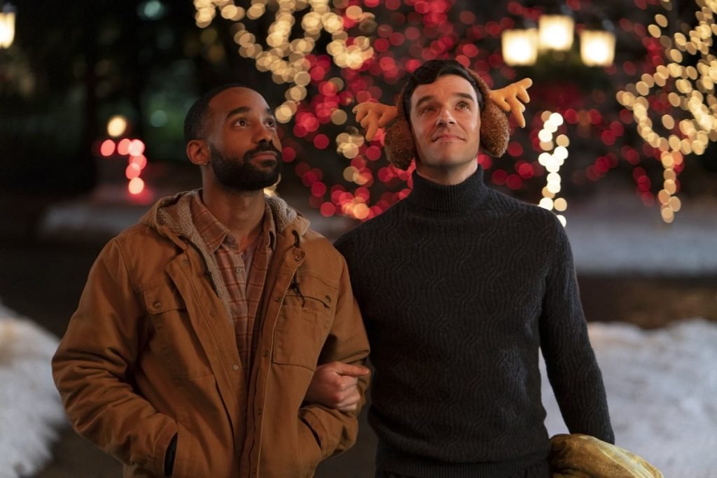 foto de dois homens com roupas de frio e luzes de natal ao fundo
