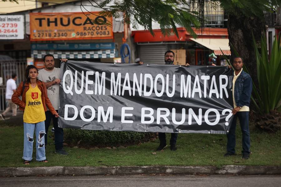 Pessoas segurando placa com os dizeres
