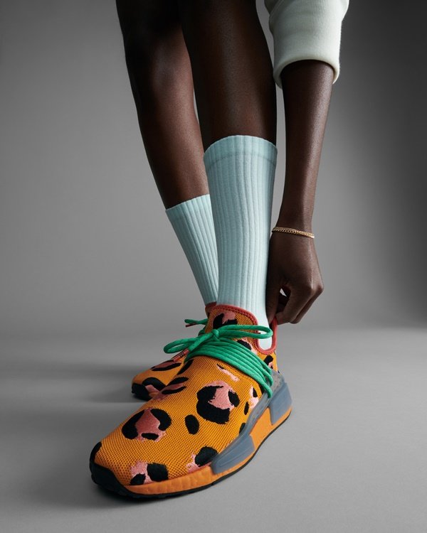 O modelo de tênis Hu NMD, desenhado por Pharrell Williams para a marca Adidas. O item é laranja, com estampa de onça, cadarços verde e solado cinza.