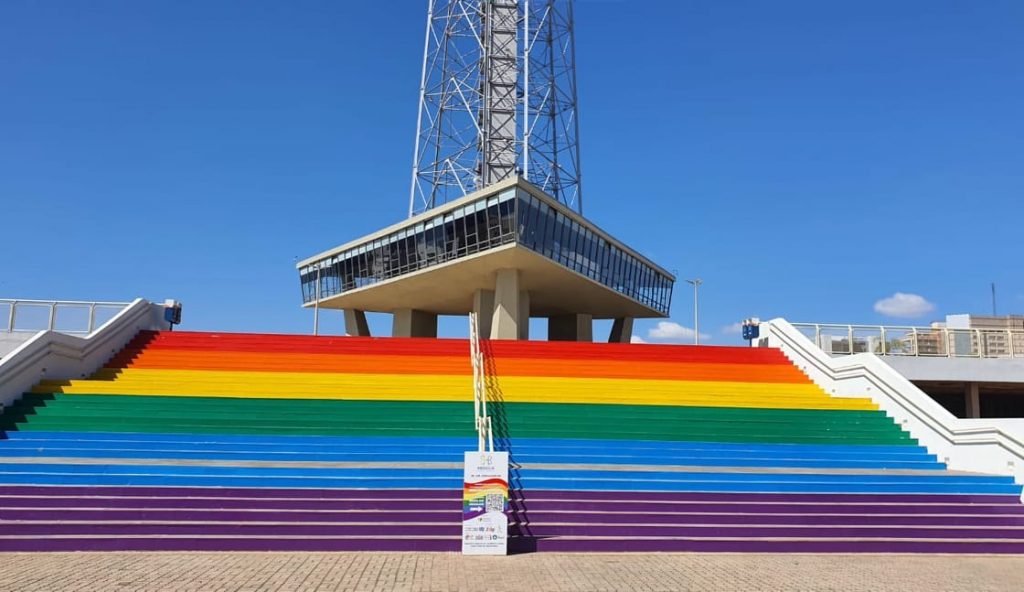 Foto de uma escada colorida com uma torre ao fundo