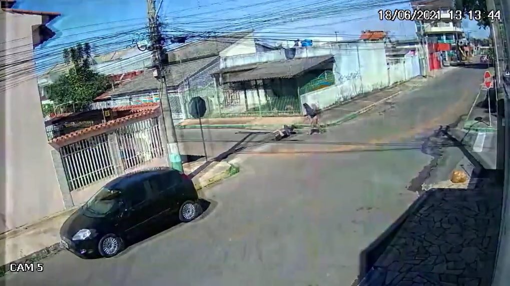 Carro estacionado na rua mulheres correndo atrás de outro carro que está sendo roubado