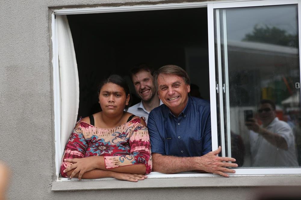 Bolsonaro ao lado de uma mulher em uma janela-Metrópoles