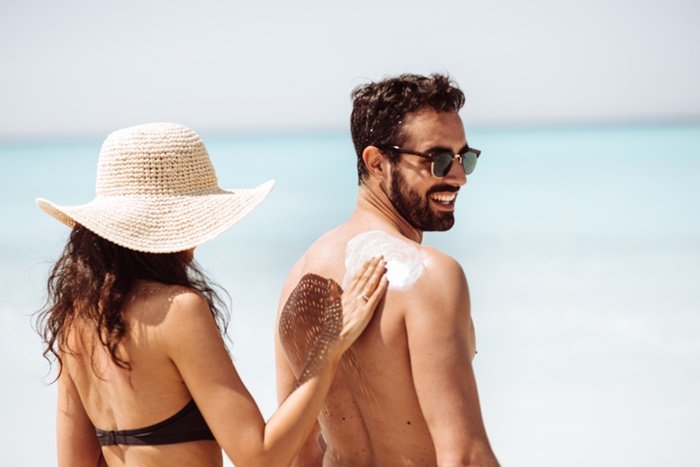 Woman applying sunscreen to a man - Metropolis