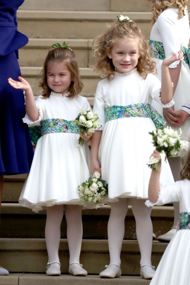 Foto colorida. Duas meninas com roupas brancas de dama de honra e um buquê na mão