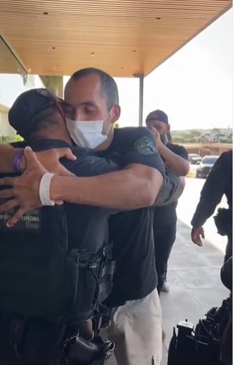 Fotografia colorida de policiais fardados se abraçando