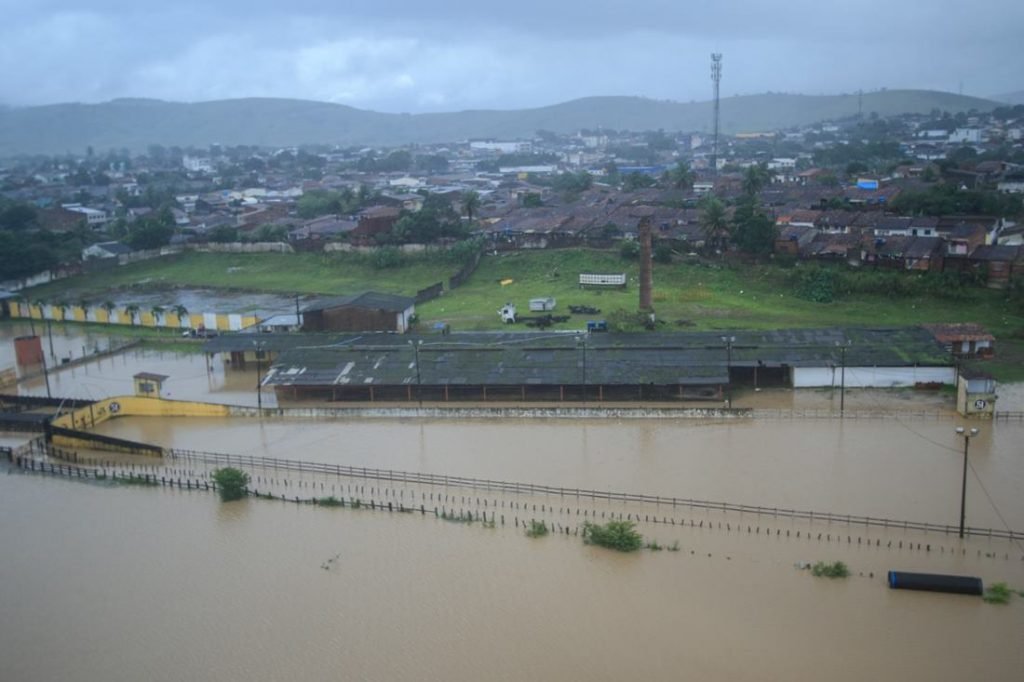 Município alagado em Alagoas após período de fortes chuvas. Uma cidade é mostrada nublada com rua completamente submersa - Metrópoles