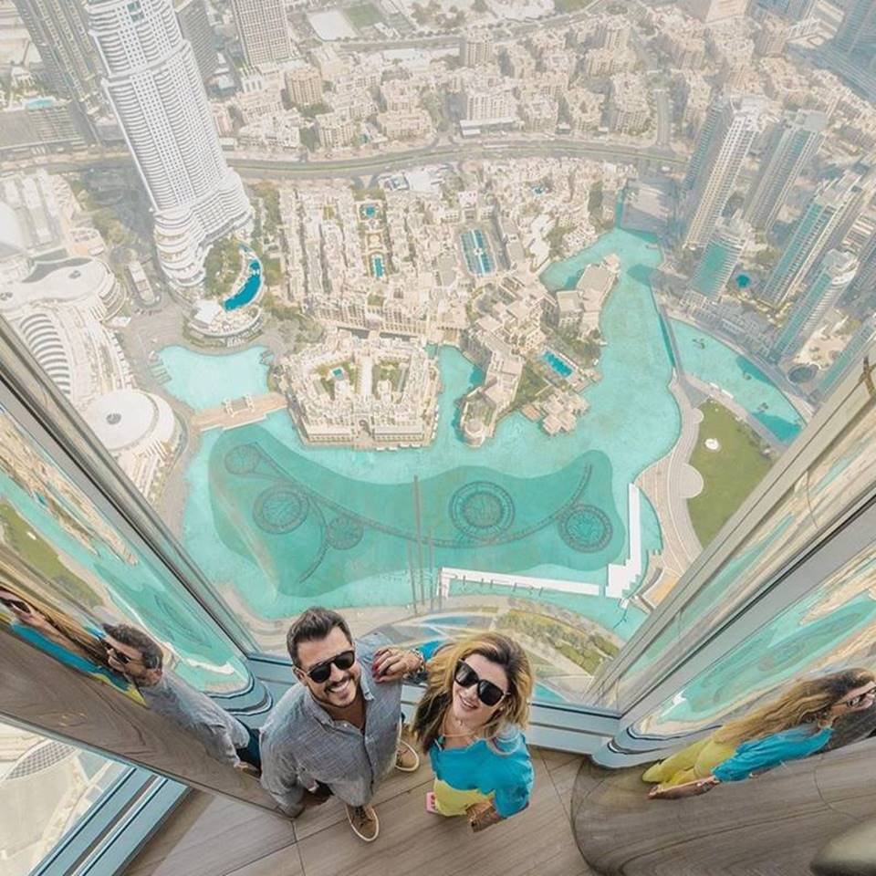 homem e mulher posam no alto de predio com vista do que há embaixo