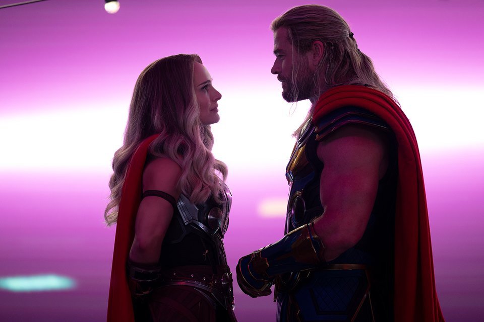 A atriz Natalie Portman e o ator Chris Hemsworth contracenam, frente a frente e caracterizados com roupas de super hérois, em cena de filme "Thor: Amor e Trovão" - Metrópoles