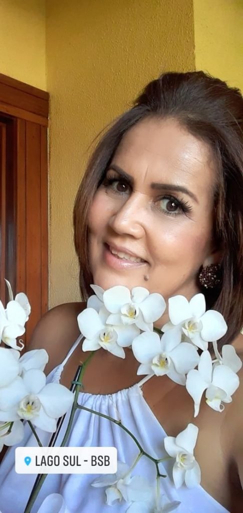 Gisele Boaventura Silva, mulher que morreu arremessada de plataforma da Rodoviária do Plano Piloto, em foto. Ela sorri e é branca, tem cabelo chanel liso e segura flores brancas - Metrópoles