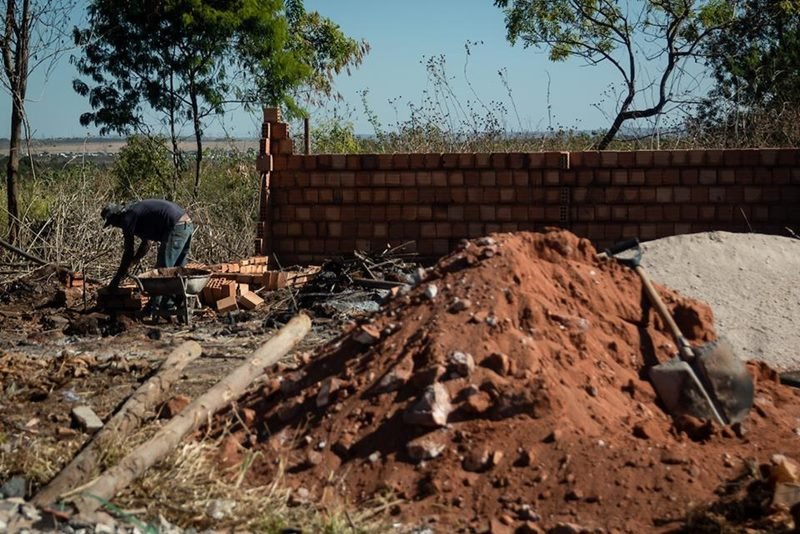 Operários trabalham construindo casas de alvenaria pequenas construídas em descampado numa invasão do Sol Nascente próxima à parque. É possível ver muito lixo na construção - Metrópoles