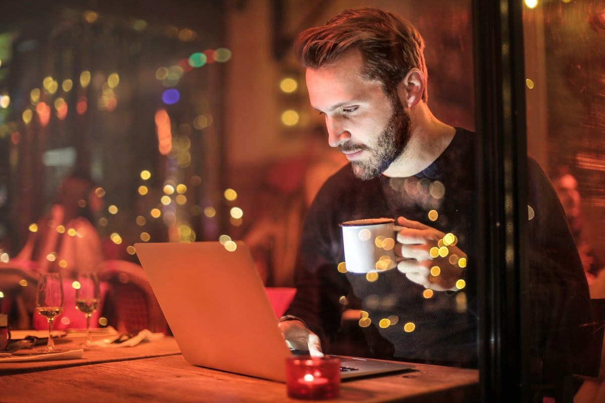Homem segurando xícara e usando o computador