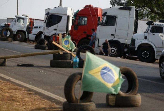 Pneus com bandeira do Brasil em frente a caminhões estacionados- Metrópoles