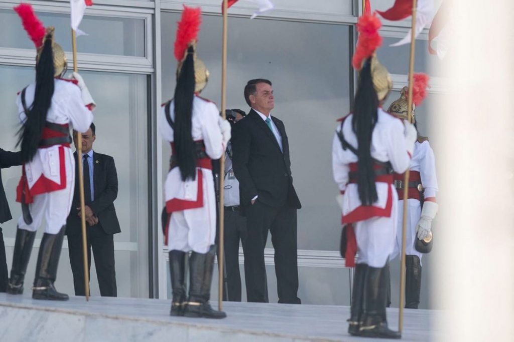 O presidente Jair Bolsonaro observa o movimento da rua, com as mãos no bolso do terno, na rampa do Palácio do Planalto. Diante dele, os Dragões da Independência - Metrópoles
