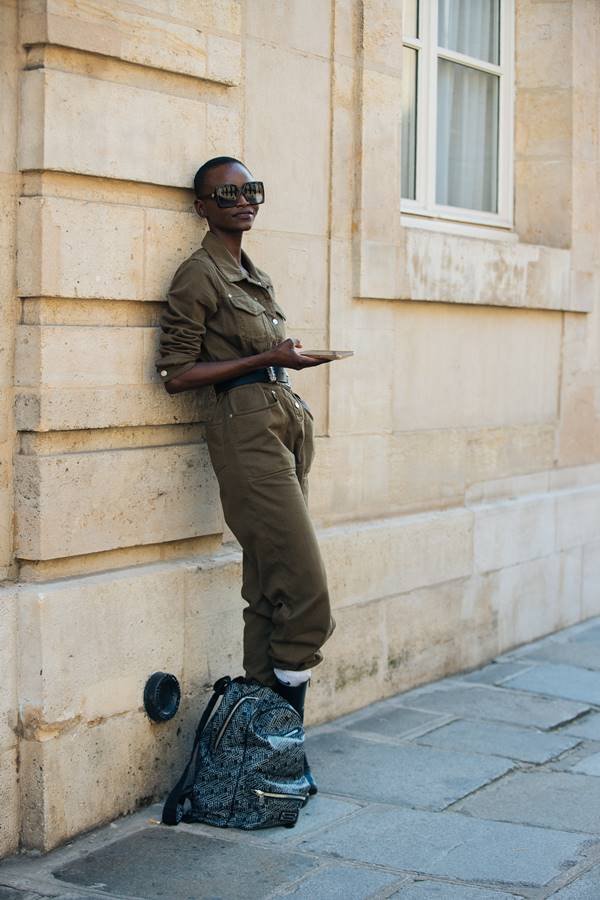 Mulher negra usa óculos escuros com macacão verde musgo utilitário