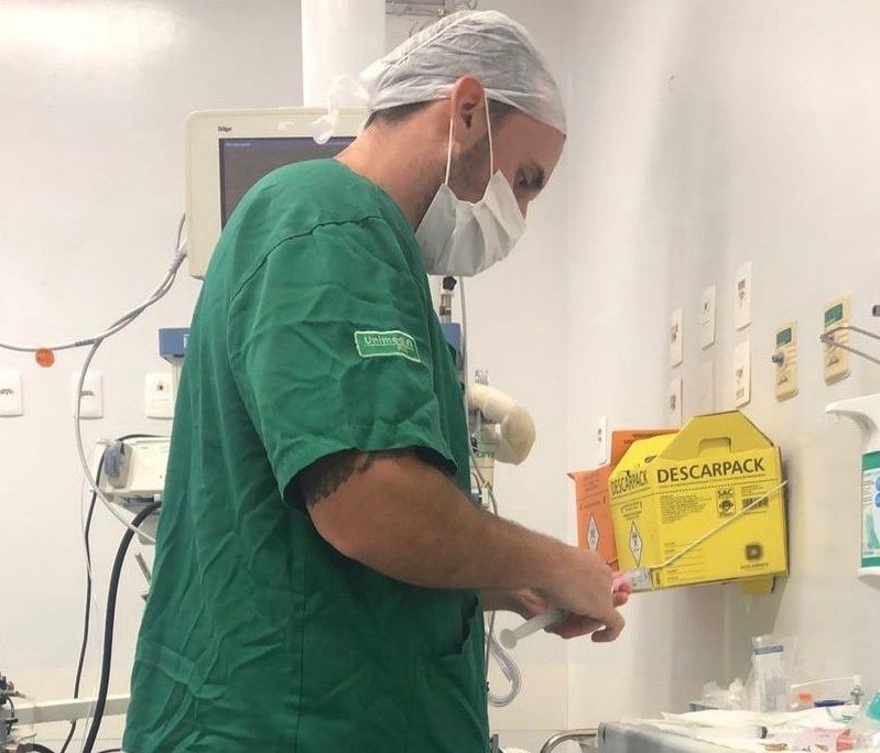 Anestesista Giovanni Quintella Bezerra, flagrado estuprando mulher grávida durante parto, fotografado preparando anestesia para cirurgia. Ele usa uniforme e máscara - Metrópoles