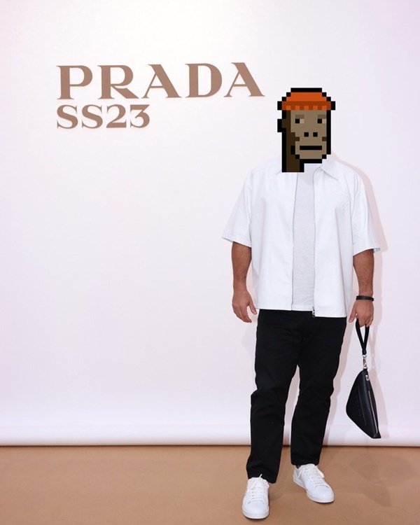 O investidor de NFT GMoney, um homem branco e jovem que esconde sua identidade com o desenho de um emoji pixelado de macaco. Na foto, ele está no desfile da Prada e usa uma camisa branca com calça preta