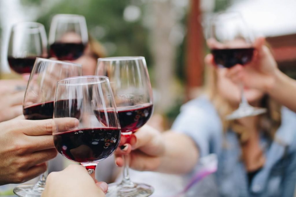 Foto colorida de pessoas tomando vinho