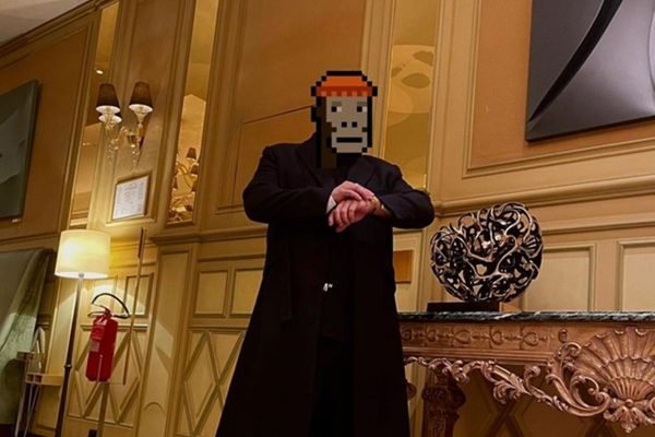 O investidor de NFT GMoney, um homem branco e jovem que esconde sua identidade com o desenho de um emoji pixelado de macaco. Na foto, ele está com uma roupa toda preta e tênis branco da Adidas