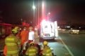 Bombeiros abaixados em pista e ambulância à frente, à noite
